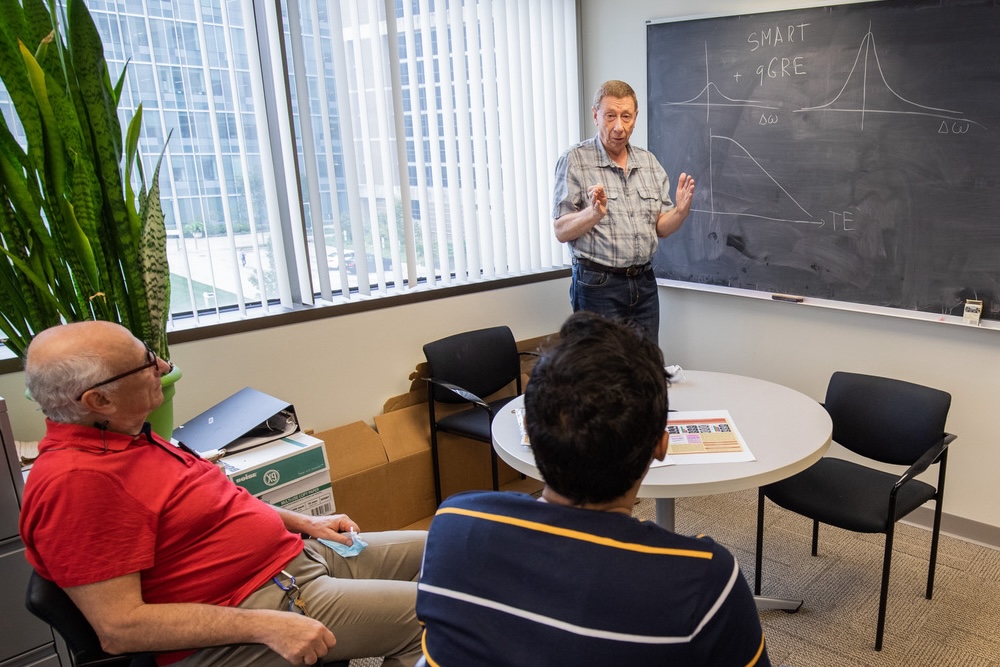 Dmitriy Yablonskiy, PhD, stands in front of a chalkboard during a meeting with members of his lab. 