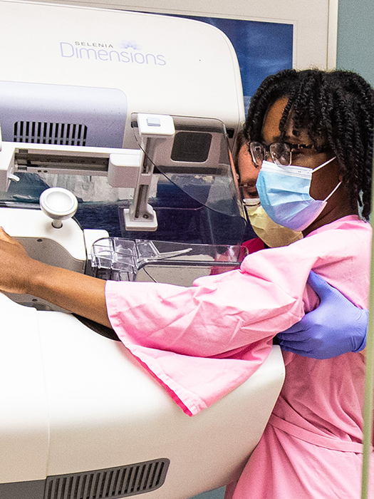 A radiology technician guides a patient during a 3D breast mammogram.