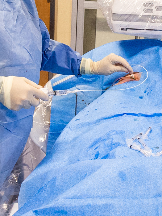 The steady hands of an interventional radiologist at MIR as they make an injection into a patient