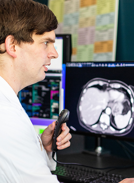 Abdominal radiologist David Ballard, MD, speaks into a recorder to digitally dictate his notes while reading a patient's scan.