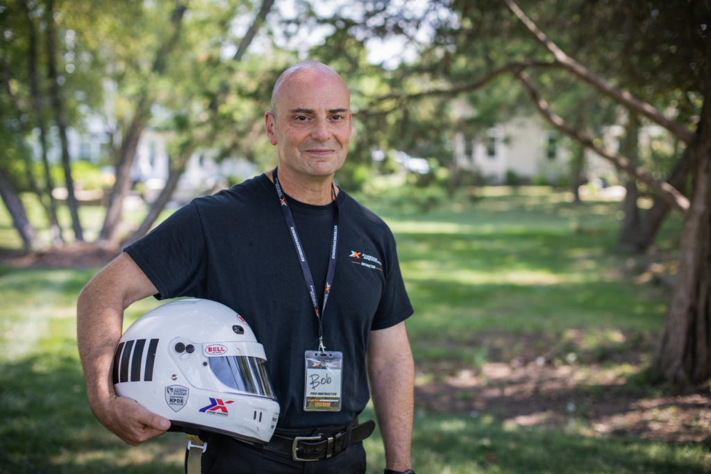 Bob Mondschein stands outside with his sports car driving helmet tucked under his arm, an activity he can continue thanks to a prostatic artery embolization.