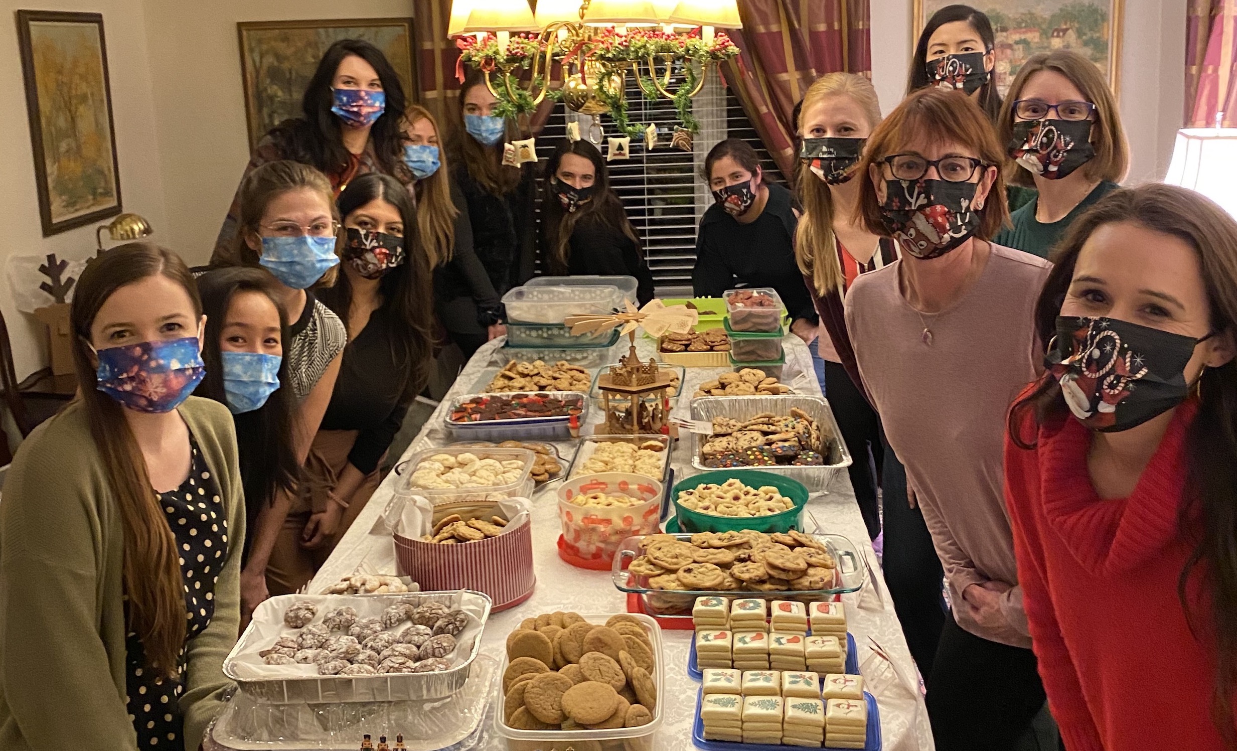 Faculty members and residents wearing face masks gather around a table of cookies during the annual MIR Holiday Cookie Exchange.