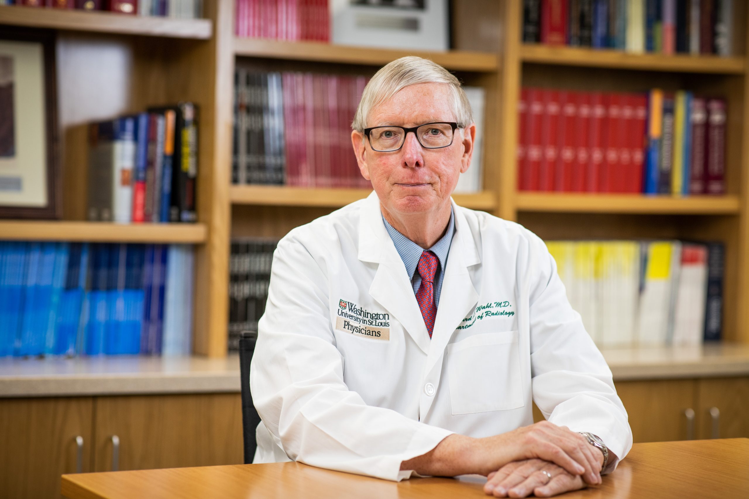 MIR Director Richard Wahl, MD, sits at a table in front of a bookcase.