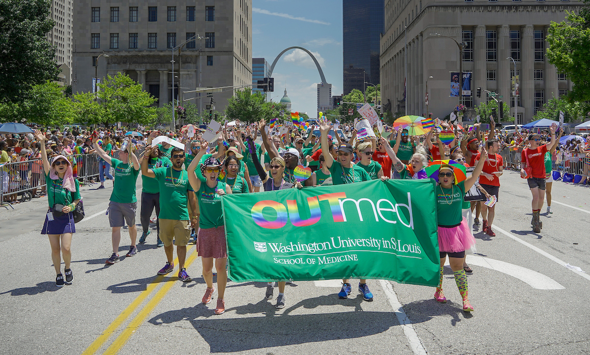 A group of people from OUTmed, Washington University's LGBTQIA+ advocacy community, carry a large green banner and march on Market Street in downtown St. Louis during the 2019 PrideSTL PrideFest parade.