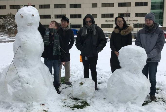 Members of the Functional Neuroimaging and Biophotonics Lab build snowmen outside of the Couch Biomedical Research Building.