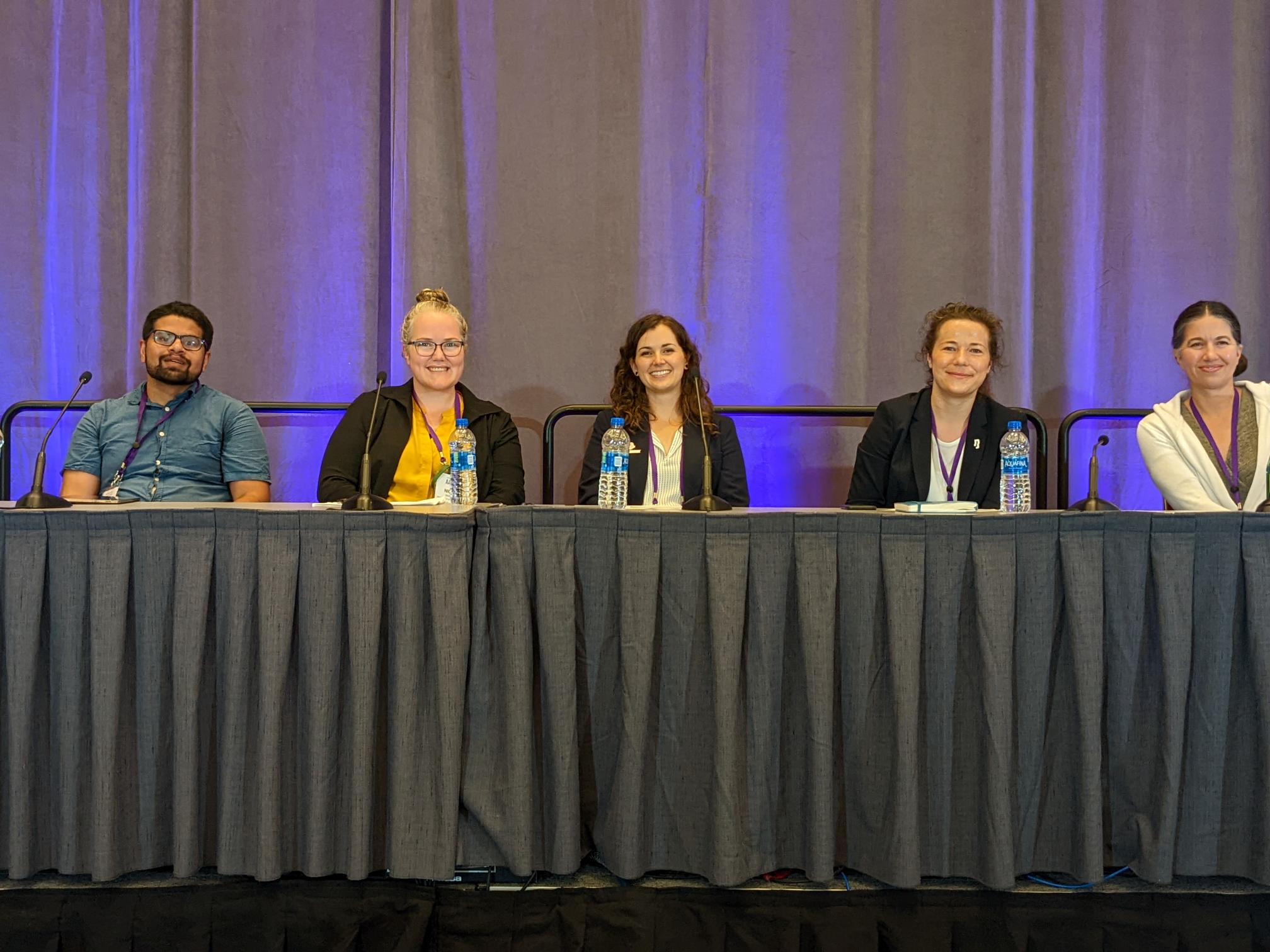 Five people sit at a table during a panel discussion.