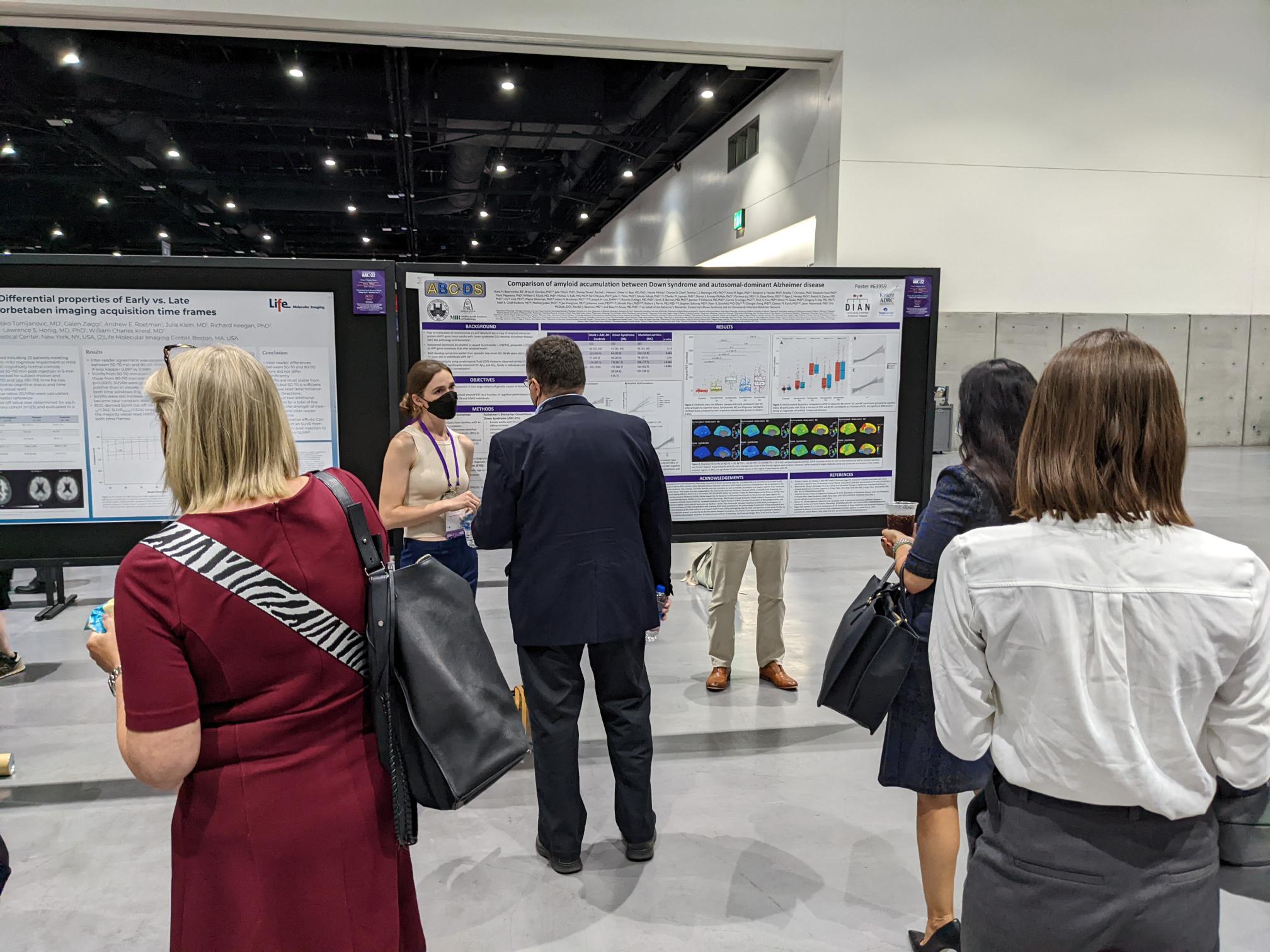 Alzheimer's Association International Conference attendees stand in a room talking to one another and looking at research posters.
