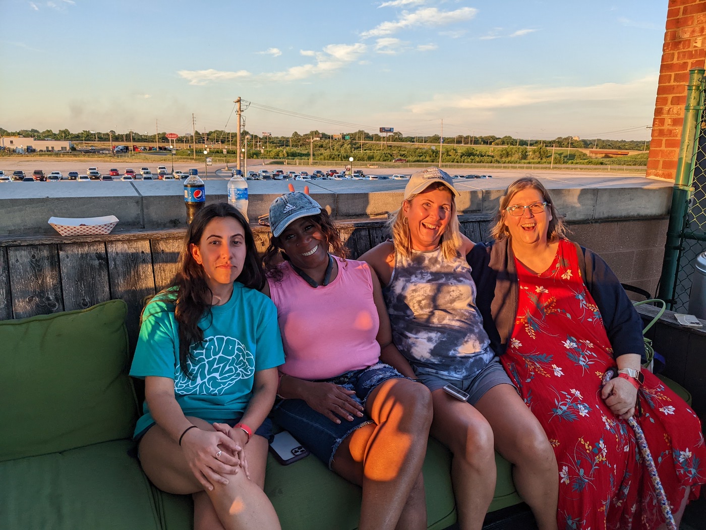 Four women sit and smile at the camera while attending the Gateway Grizzlies baseball game.