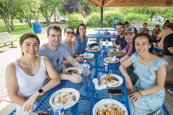 Residents enjoy lunch at a picnic table during the annual Residency Welcome BBQ at Faust Park.