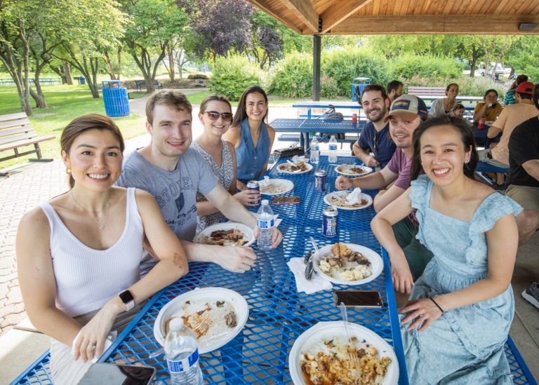 Residents enjoy lunch at a picnic table during the annual Residency Welcome BBQ at Faust Park.