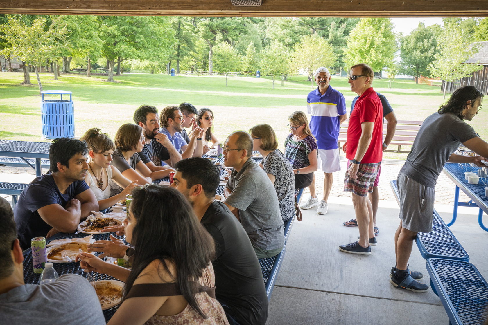 Attendees walk around and sit at picnic table during the annual Residency Welcome BBQ at Faust Park.