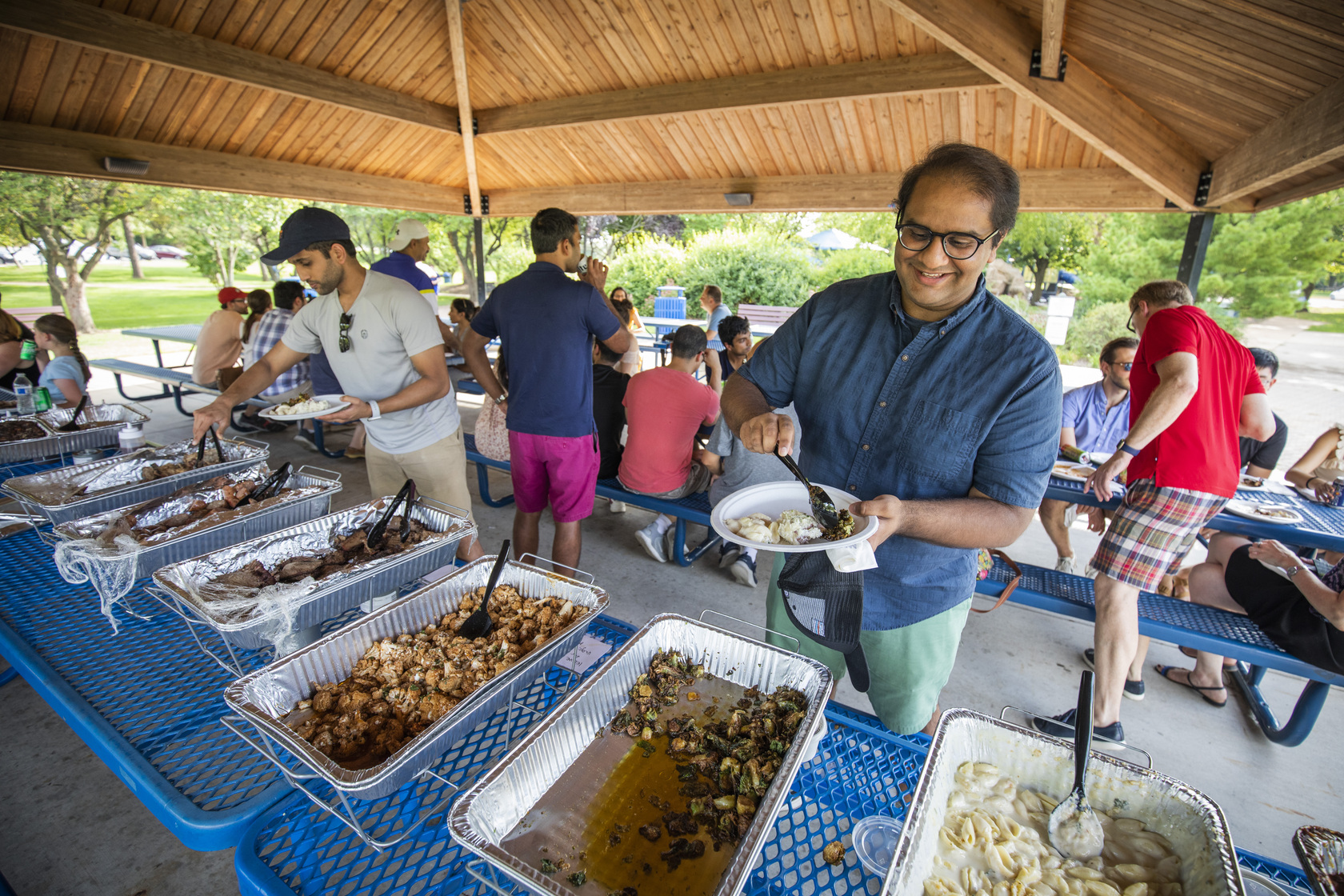 An attendee serves themselves food from the buffet line at the annual Residency Welcome BBQ at Faust Park.