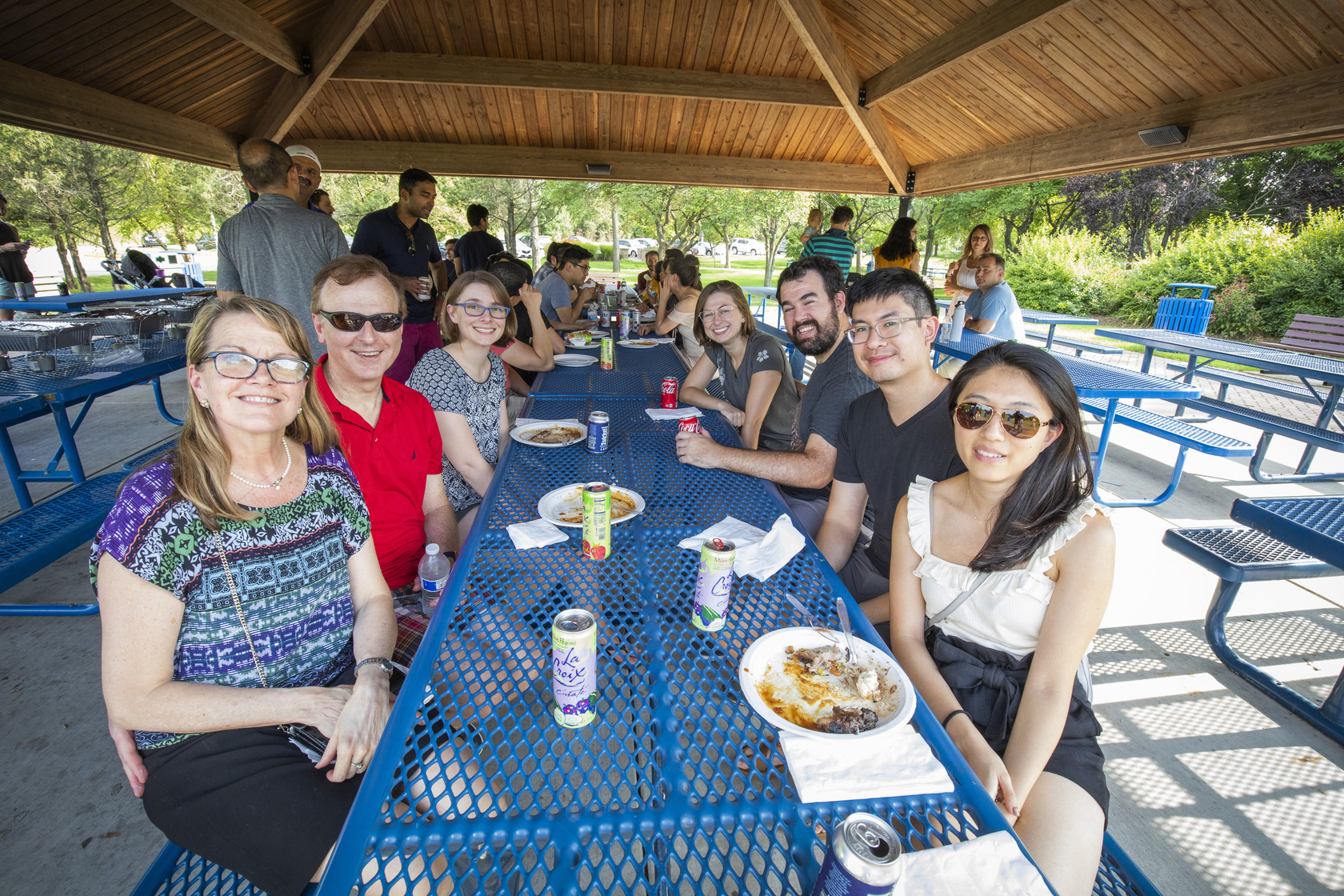 Attendees at the annual Residency Welcome BBQ at Faust Park sit at a picnic table and smile.