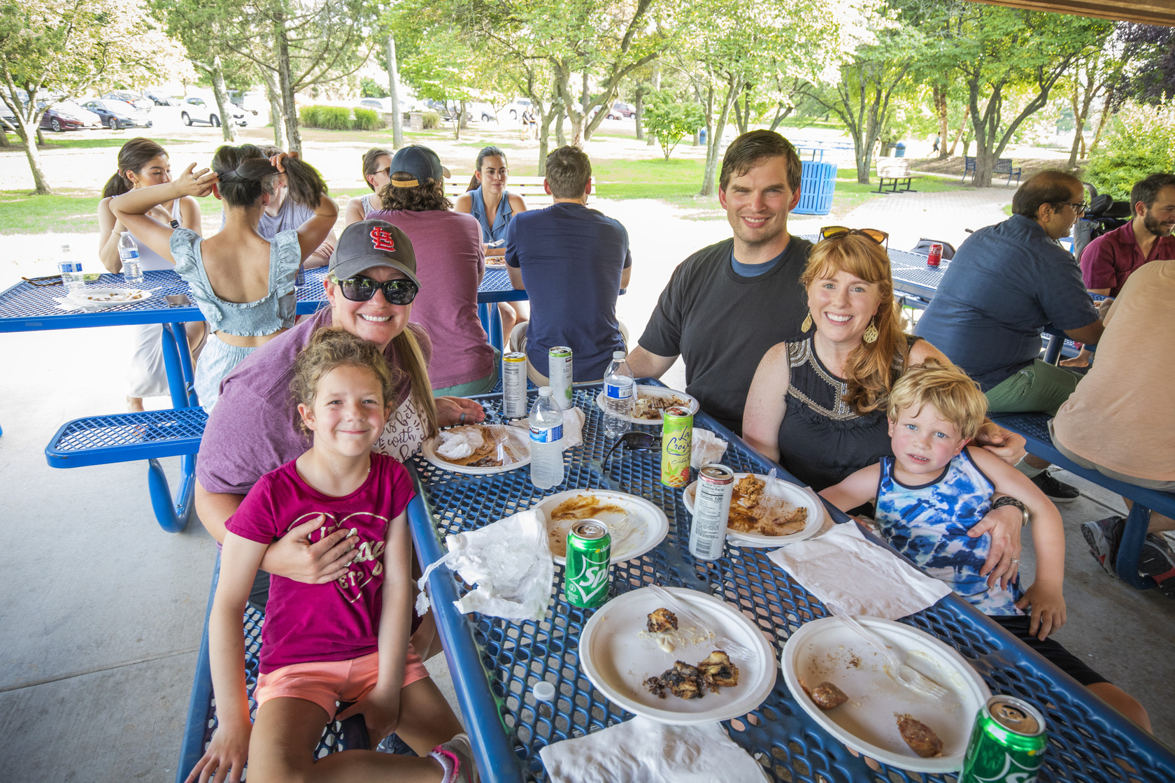 Attendees at the annual Residency Welcome BBQ at Faust Park sit at a picnic table and smile.