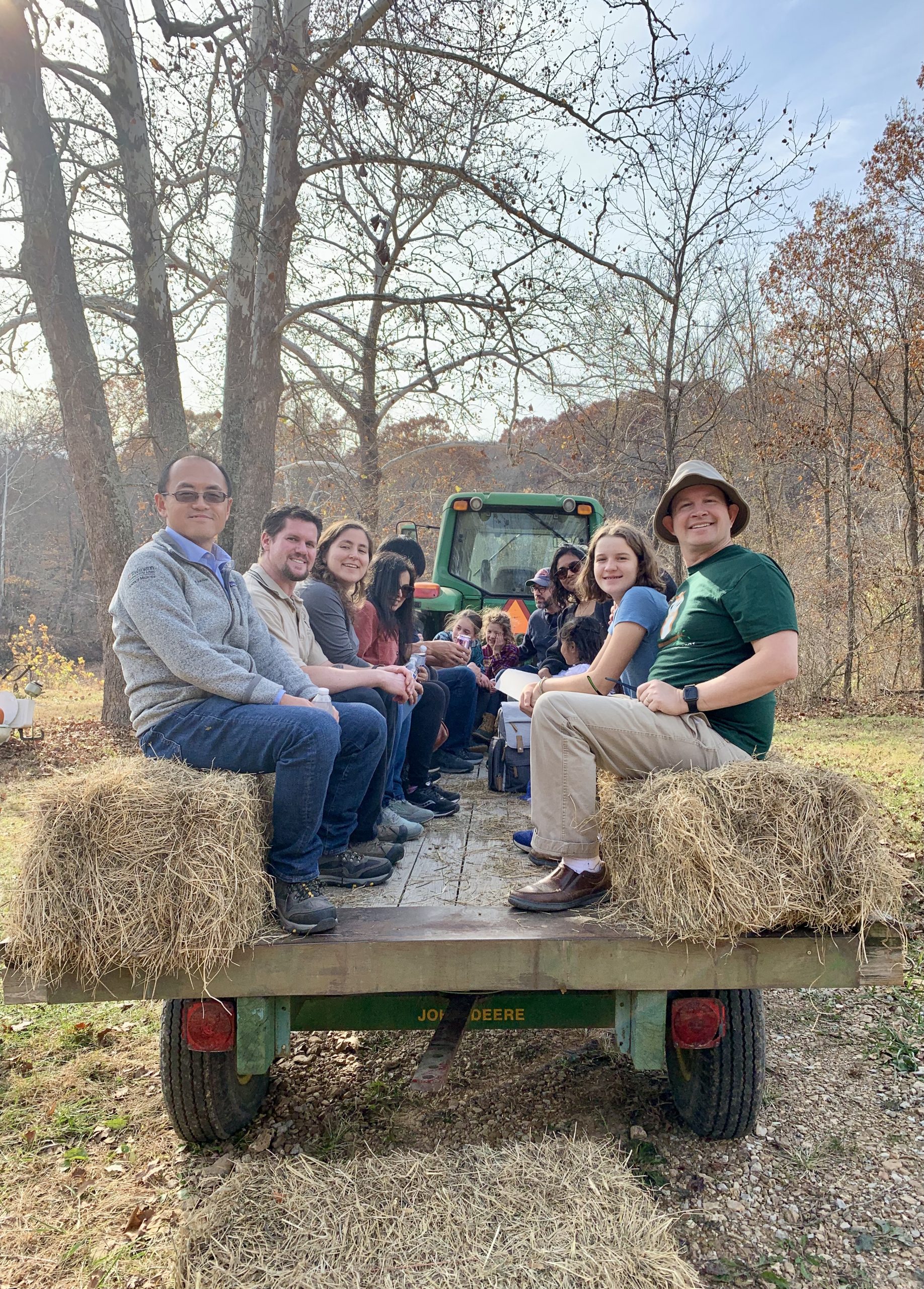 MIR faculty, staff, trainees and their families sit on the back of a trailer for a fall hayride at the annual visit to the Hulett Farm.