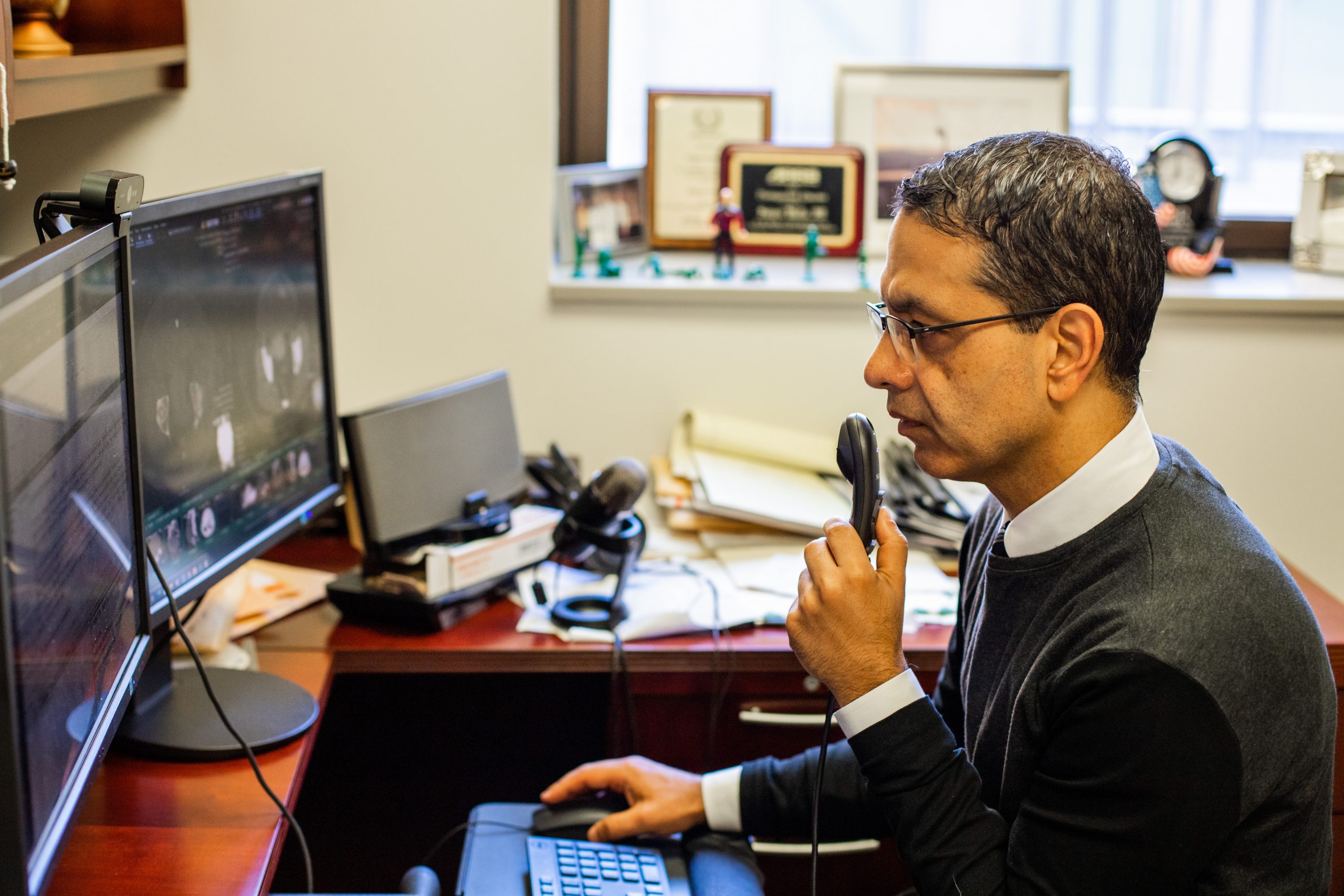 Sanjeev Bhalla, MD, sits at a desk and dictates imaging findings in his office.