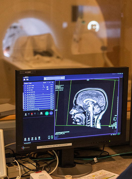 A scan of a research participant's head is displayed on a computer screen in a control room in the Center for Clinical Imaging Research.