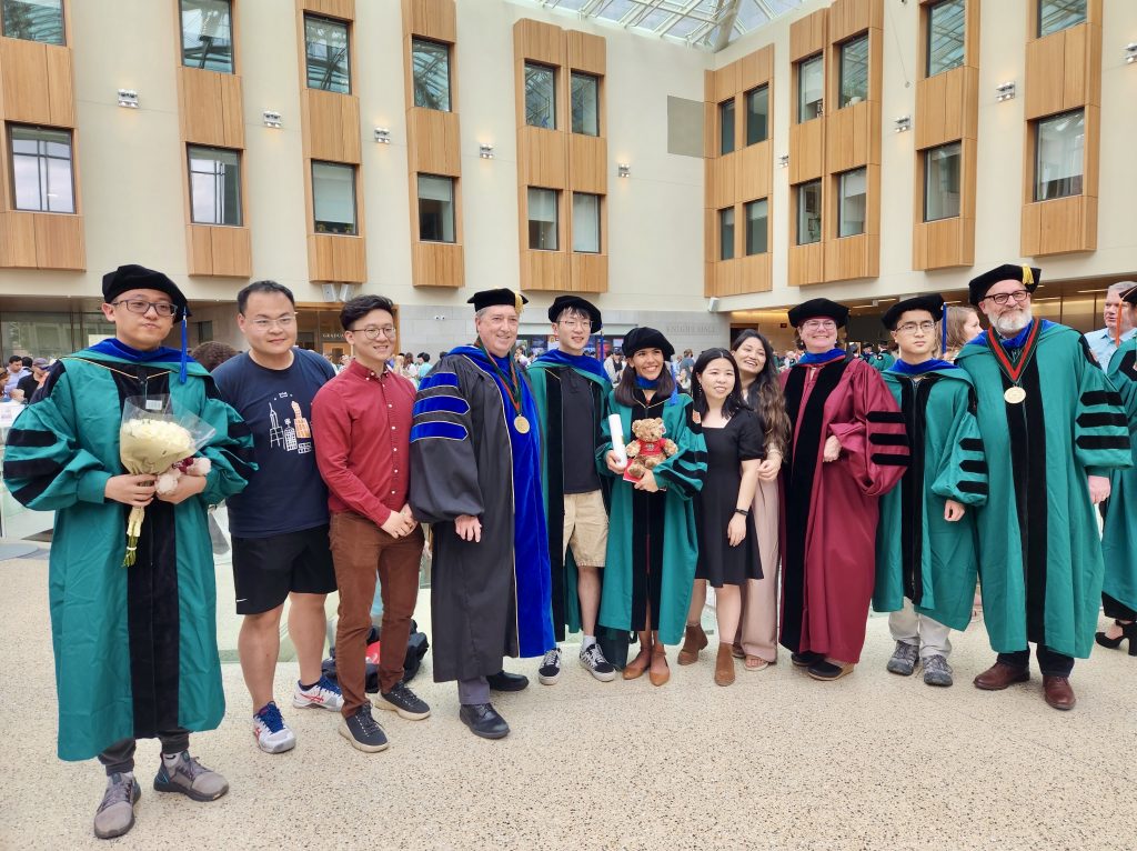 Faculty and students wearing graduation gowns pose for a photo during WashU 2023 commencement.