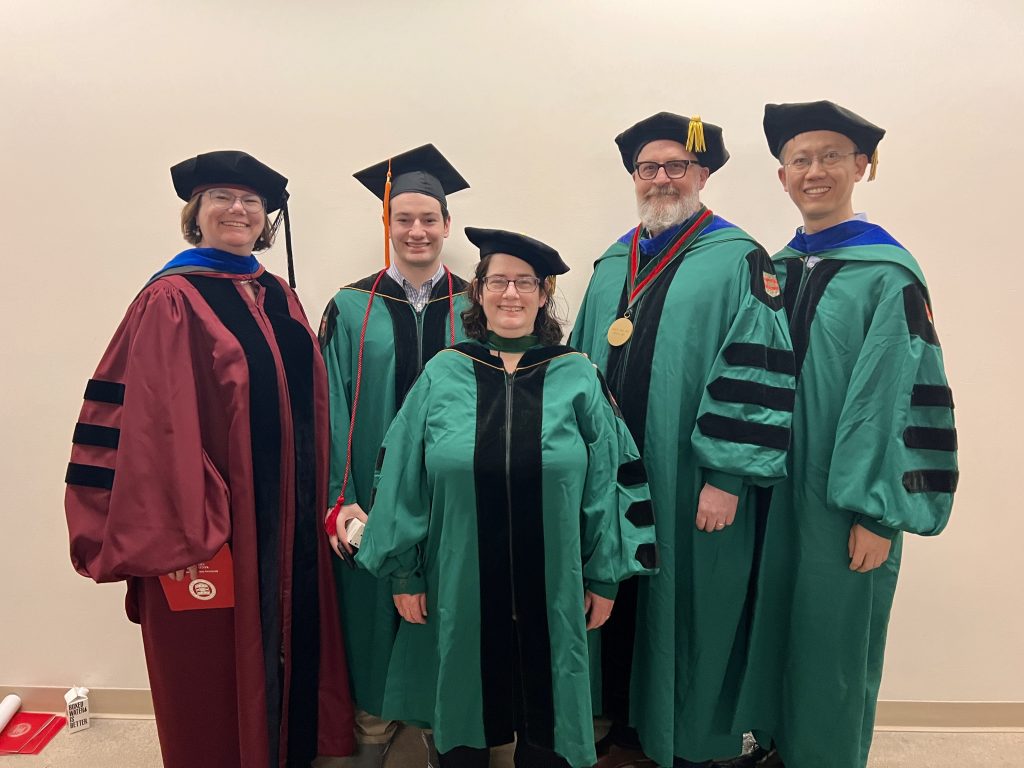 Tammie Benzinger, MD, PhD, and colleagues — dressed in graduation robes — pose for a photo at WashU 2023 commencement.