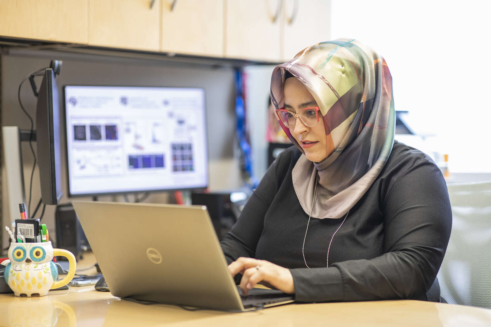 Assistant Professor Ikbal Şencan-Eğilmez, PhD, types at a laptop in her office.