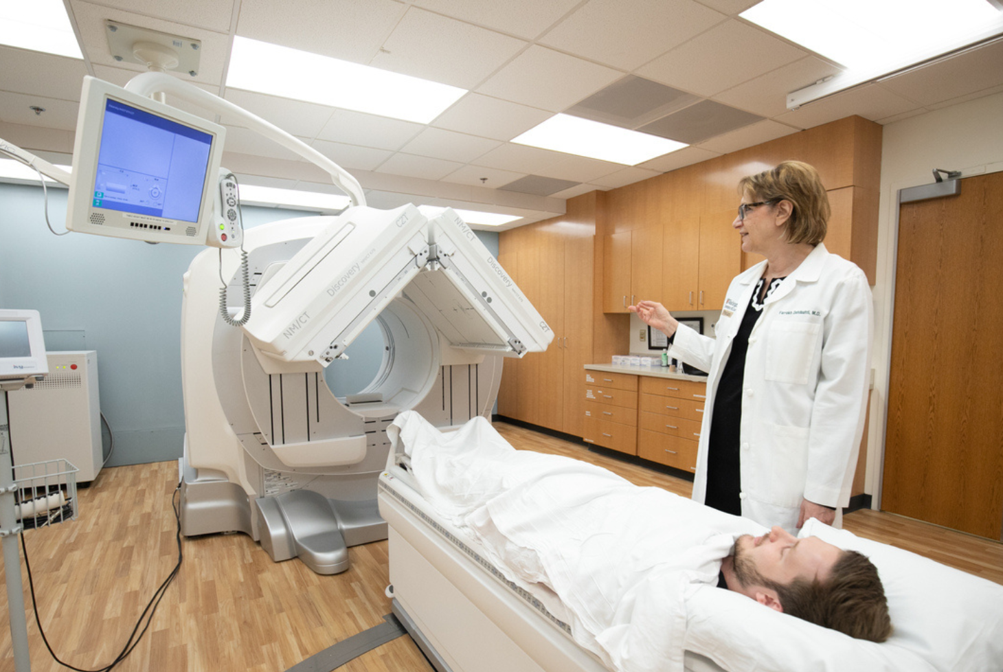 Farrokh Dehdashti, MD, the Drs. Barry A. And Marilyn J. Siegel Professor of Radiology, points to a CT scanner as she stands next to a patient is being prepared to be examined.