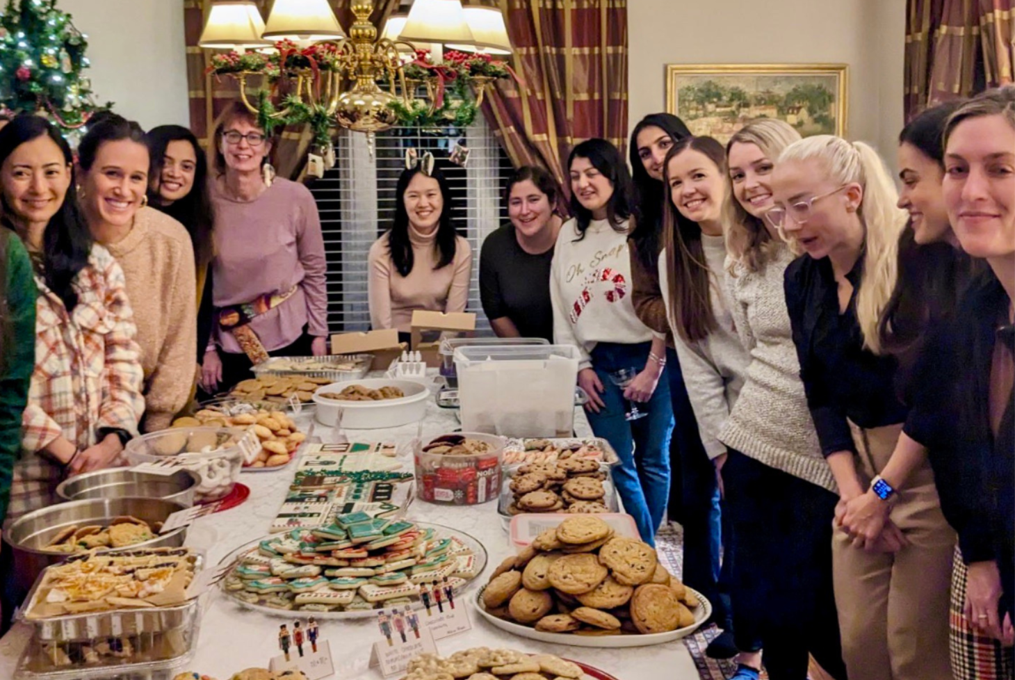 MIR trainees smile around a dining room table filled with homemade cookies at the 2023 Cookie Exchange.