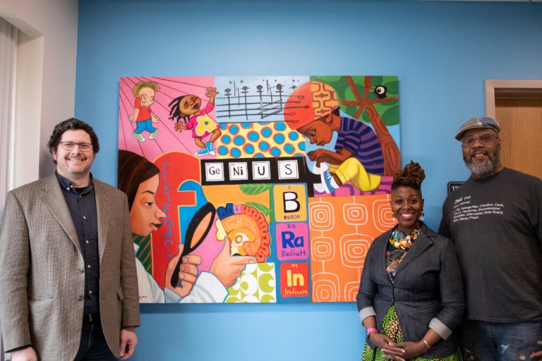 Mural zoomed in image of woman next to the words Discovery and Wonder The artist cbabi bayoc stands in front of the mural with center director Adam T. Eggebrecht