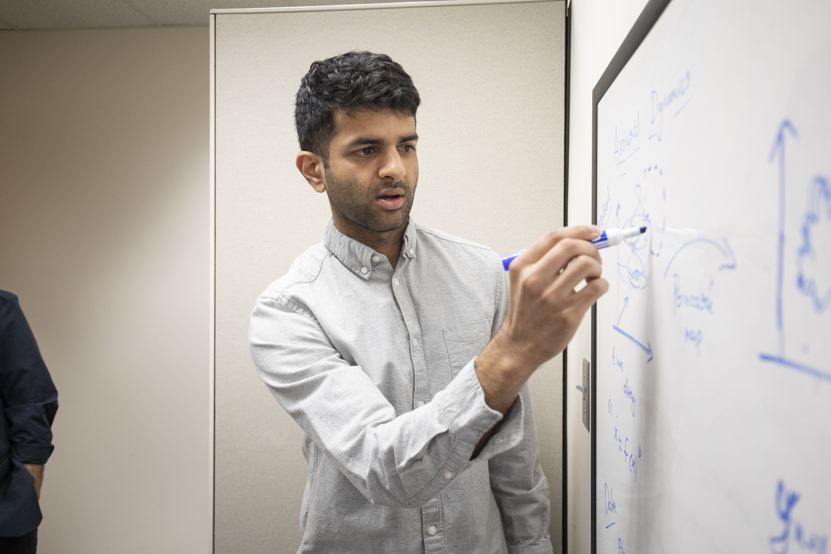 Ryan Raut, PhD, writes on a whiteboard.