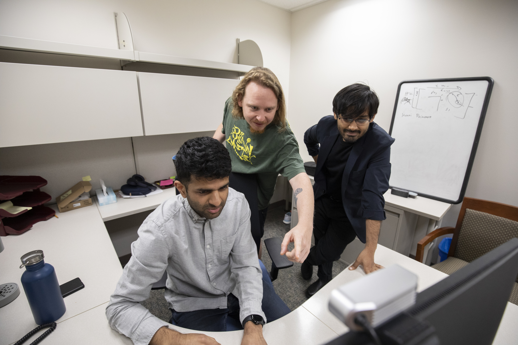 Ryan Raut, PhD, and two lab members look at a computer monitor.