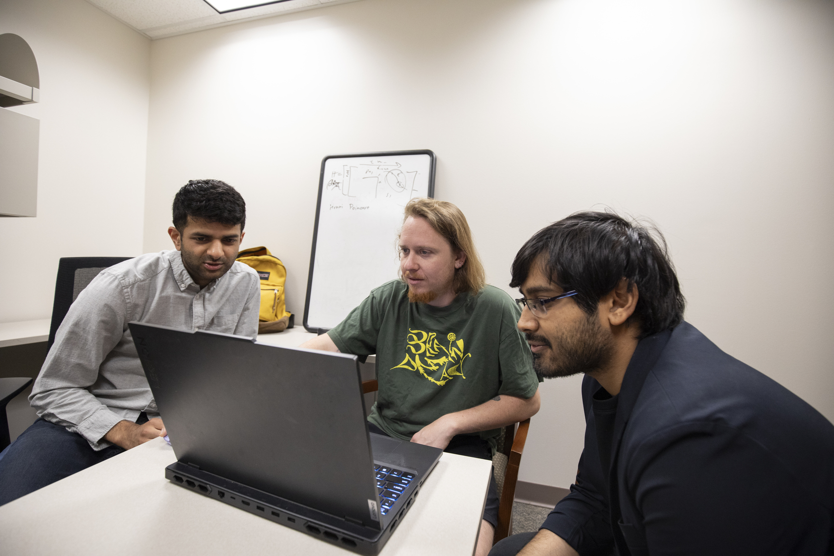 Ryan Raut, PhD, and two members of his lab look at a computer monitor.