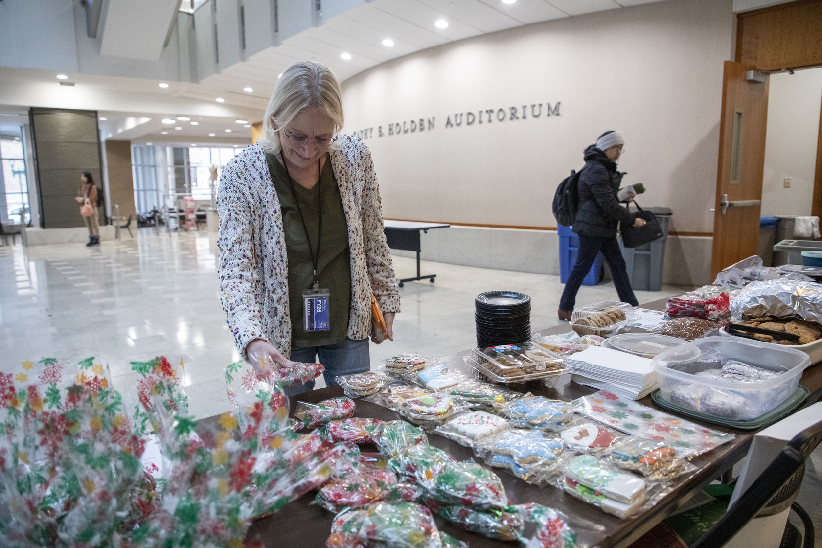 A bake sale attendee smiles and grabs a cookie from the resident bake sale table.