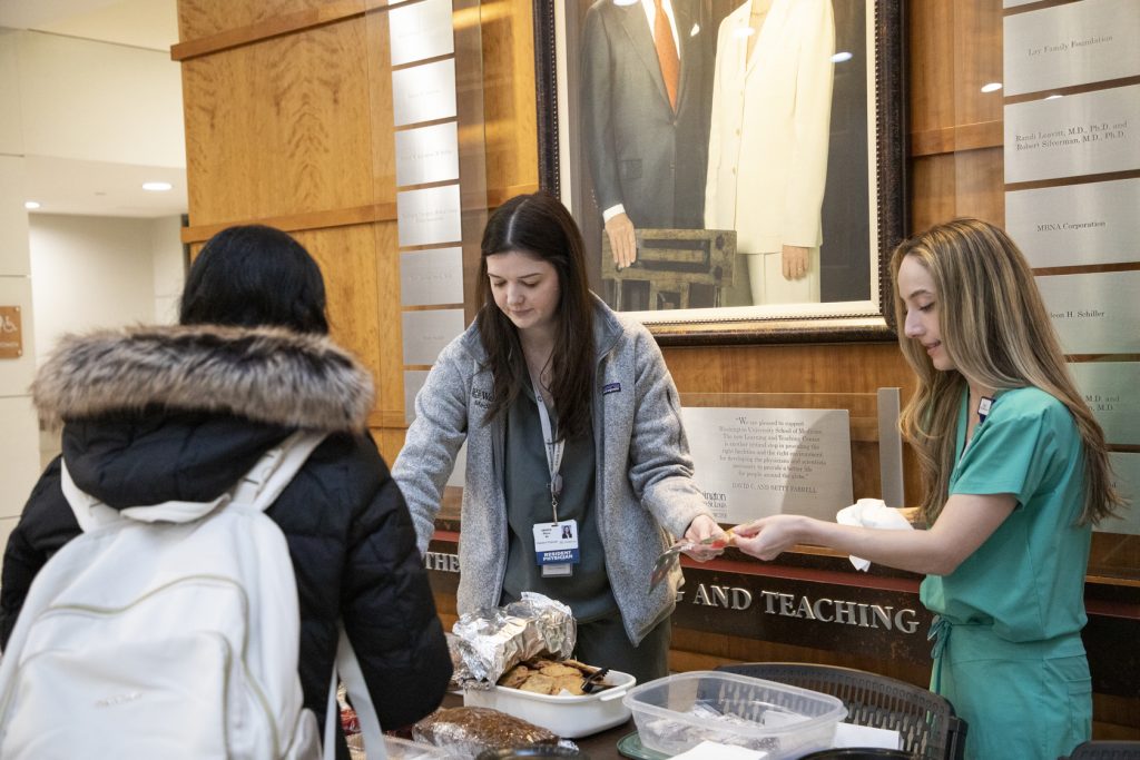 Residents stand behind their bake sale table full of treats.
