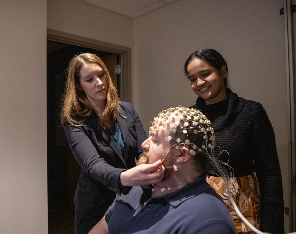 Muriah D. Wheelock, PhD, and a trainee in her lab adjust a non-invaise imaging cap on a research study particpant.