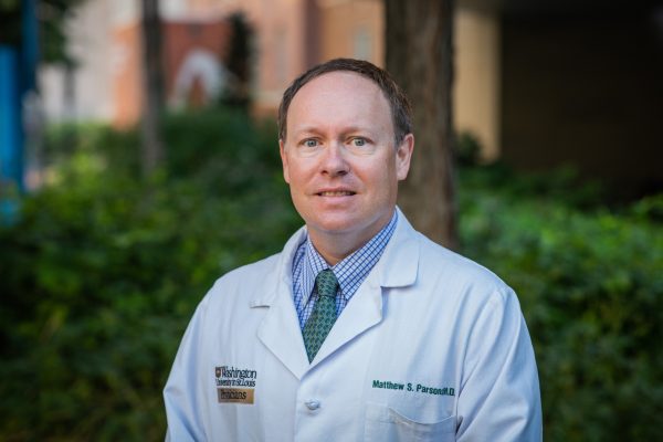 Headsahot of Matthew Parsons, MD, wearing a white coat in an outdoor setting