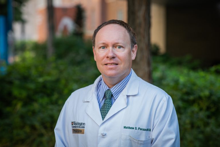 Headsahot of Matthew Parsons, MD, wearing a white coat in an outdoor setting