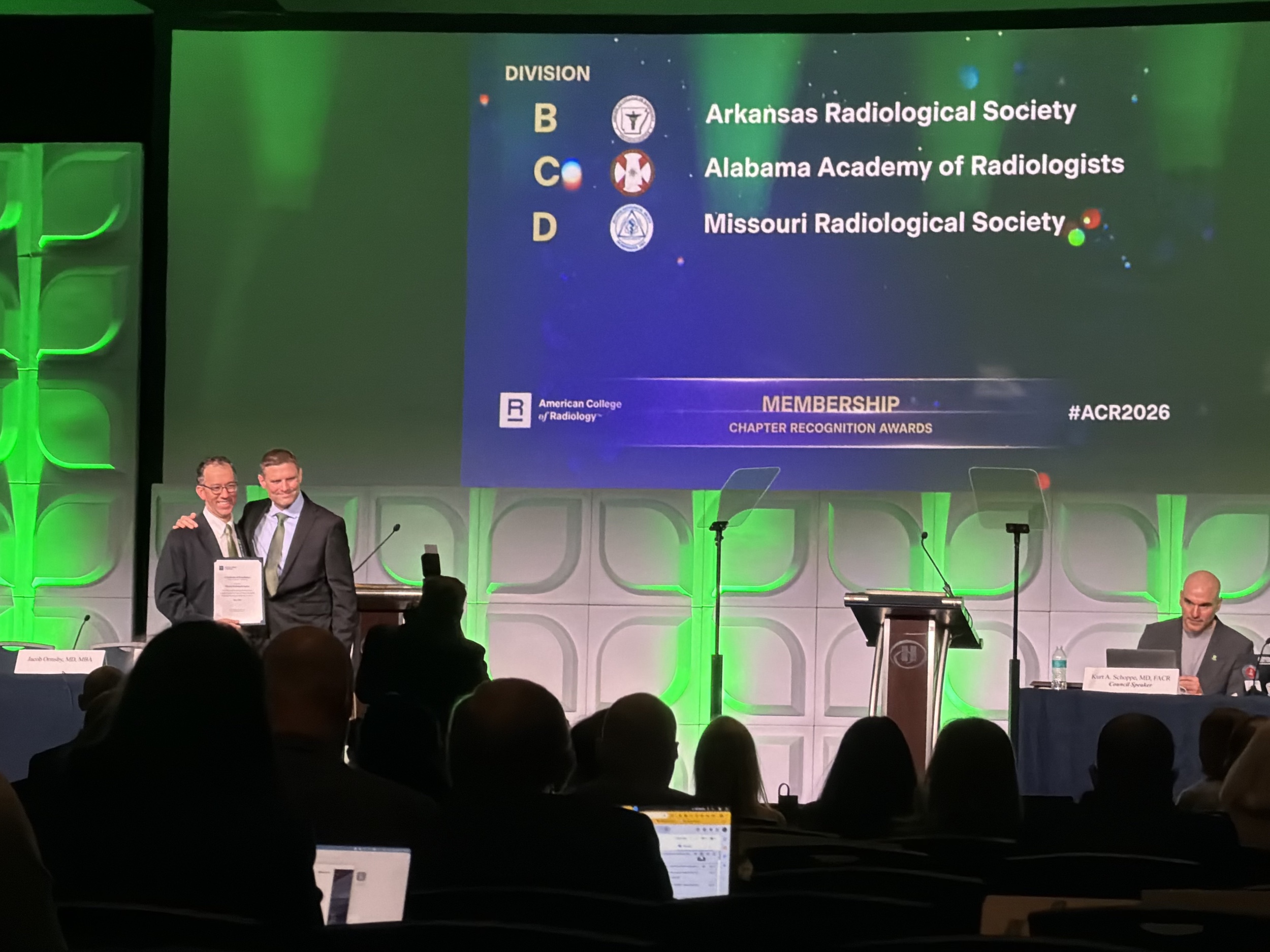 Two men stand on a stage accepting an award